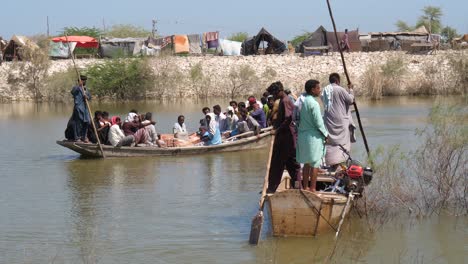 Dolly-Left-Reveal-Flood-Victims-On-Boat-With-Belongings-Going-Past-On-River-In-Sindh