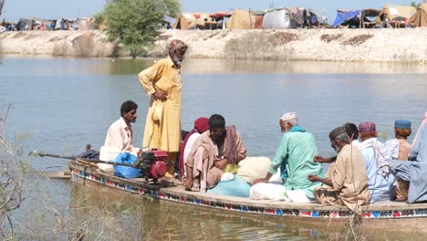 Flutopfer-Auf-Einem-Boot-Mit-Habseligkeiten,-Die-Auf-Dem-Fluss-In-Sindh-Vorbeifahren