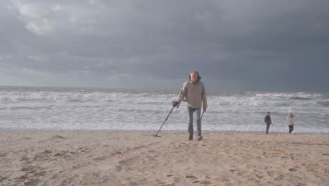 Man-Using-Metal-Detector-On-The-Beach-In-De-Haan,-Belgium---wide