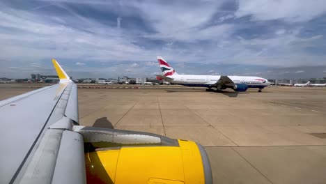 View-of-yellow-airplane-wing-and-engine-taxiing-in-London-Gatwick-British-airport-in-UK