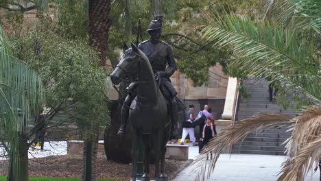 Close-up-shot-of-the-Scout-sculpture,-South-African-War-Memorial-at-Anzac-square-with-office-workers-rushing-home-towards-underground-railway-station-at-central-business-district,-Brisbane-city