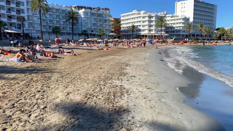Famous-summer-vacation-destination-Ses-Figueretes-beach-in-Ibiza-island-Spain,-people-on-holiday,-hotels-and-apartments-in-the-background,-Ibiza-town,-4K-shot
