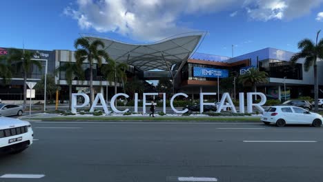 Static-shot-of-front-facade-of-pacific-fair-shopping-centre-with-block-letter-sign-at-the-front-entrance-against-blue-sky-with-car-traffics-in-the-foreground-on-a-sunny-day