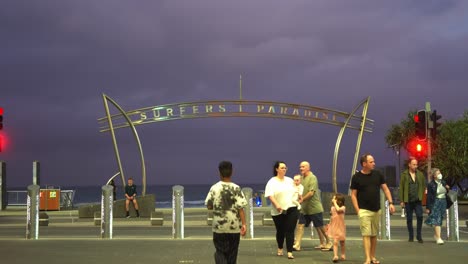 Iconic-landmark-of-surfers-paradise,-people-strolling-to-the-beach,-watching-and-observing-the-thick-layer-of-ominous-dark-clouds-covering-the-sky,-wet-and-wild-storm-season-approaching