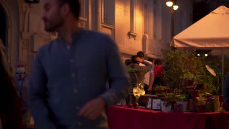 People-walking-quietly-in-slow-motion-at-night-in-a-street-next-to-a-restaurant-terrace