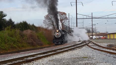 Dampflokomotive-Bläst-Schwarzen-Rauch-Und-Dampf,-Während-Sie-An-Einem-Wintertag-Eine-Station-Herauszieht