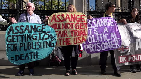 In-Zeitlupe-Halten-Unterstützer-Von-Julian-Assange-Bunte-Banner,-Während-Sich-Demonstranten-Versammeln,-Um-Eine-Menschenkette-Um-Die-Häuser-Des-Parlaments-Zu-Bilden,-Die-Die-Freilassung-Des-Wikileaks-gründers-Aus-Dem-Gefängnis-Fordern