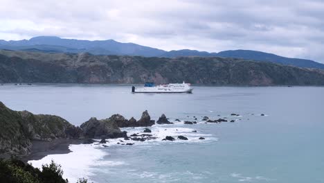 Interislander-passenger-and-vehicle-ferry-leaving-Wellington-harbour,-calm-sea-water,-rugged-rocky-landscape,-en-route-to-Picton-in-the-South-Island-of-New-Zealand-Aotearoa