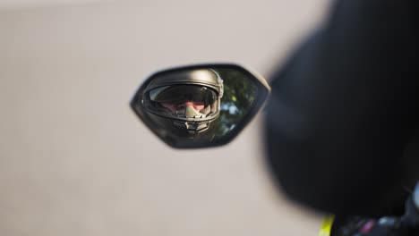 Man-on-motorcycle-reflected-in-rear-mirror-while-wearing-helmet