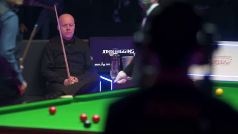 John-Higgins,-a-Scottish-professional-snooker-player,-rests-and-looks-on-at-a-play-between-sets-against-player-Marco-Fu-of-Hong-Kong-during-a-match-of-the-Hong-Kong-Masters-snooker-tournament-event