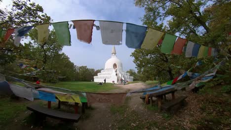 Wide-Angle-establishing-shot-of-the-Peace-Stupa-with-pray-flags-in-the-foreground-at-Zalaszántó,-Hungary
