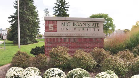 Michigan-State-University-sign-in-East-Lansing,-Michigan-with-gimbal-video-walking-forward