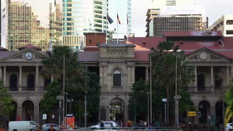 Front-facade-of-Australia-listed-heritage-building,-Brisbane-GPO-at-busy-central-business-district,-office-workers-rushing-home,-walking-through-the-laneway,-car-traffic-crossing-on-Queen-street