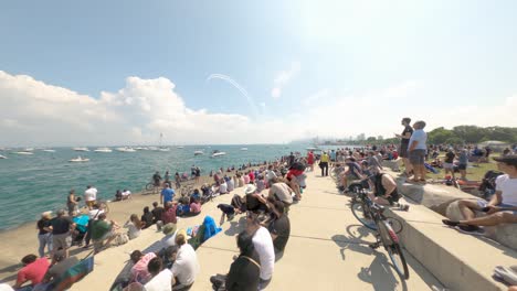 Acrobatic-airplanes-fly-in-the-distace-as-a-crowd-of-people-and-boats-watch-The-2022-Chicago-Air-and-Water-Show-on-Lake-Michigan