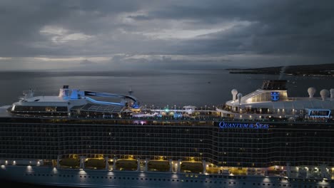 Aerial-drone-shot-over-large-Quantum-of-the-seas-cruise-ship-off-the-Lahaina-shores,-Hawaii,-USA-at-night-time