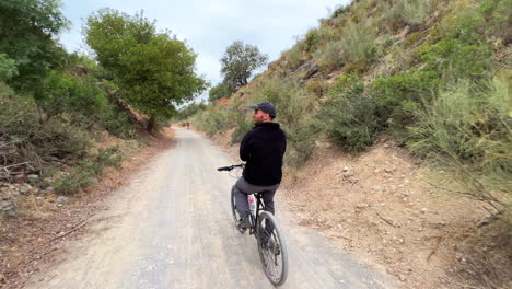 Young-man-riding-a-bicycle-with-no-hands-in-nature-on-a-mountain-in-Spain,-fun-adventure-sport-activity,-4K-action-shot