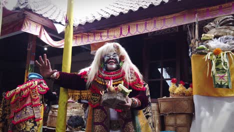 Bailarina-Balinesa-Con-Una-Máscara-Cultural-Topeng-Sidakarya,-Danza-Rezando-En-Bali-Llevando-Ofrendas-De-Incienso-Y-Flores,-Templo-En-Ubud