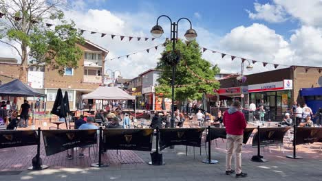 Panning-view-of-Crawley-downtown-square-with-people-enjoying-drinking-beer-outdoors-on-summer-day,-United-Kingdom