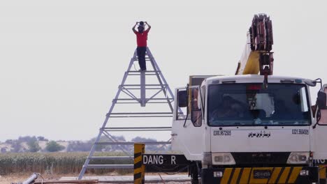 Male-Standing-On-Top-Of-Center-Pivot-Irrigation-System-Beside-Parked-Mobile-Crane-Truck-In-Sindh