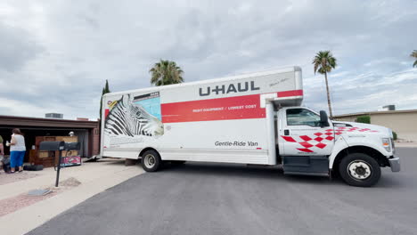 People-help-loading-a-U-Haul-truck-parked-by-a-home-in-a-residential-area