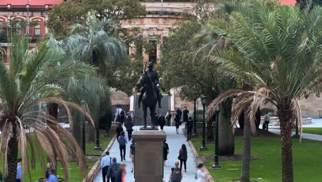 Timelapse-fast-motion-shot-capturing-busy-office-workers-rushing-home-at-5pm,-walking-fast-towards-central-station-across-war-memorial-Anzac-square-at-downtown-Brisbane-city,-Queensland,-Australia