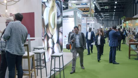 Panoramic-shot-inside-large-culinary-trade-fair,-energetic-people-walking-by,-FITUR