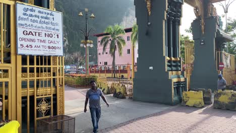 Man-walks-out-from-the-main-gate-or-entrance-of-the-famous-Batu-Caves-Hindu-Temple-in-Selangor,-Kuala-Lumpur,-Malaysia
