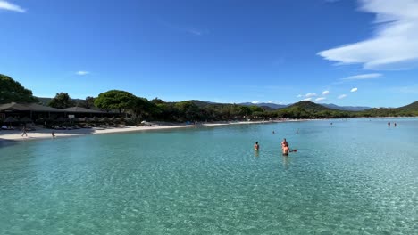 People-on-beach-and-enjoying-summer-holiday-bathing-in-Santa-Giulia-clear-sea-water-in-Corsica-island-in-France