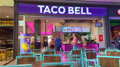 Taco-Bell-in-La-Canada-shopping-mall-in-Marbella-Spain,-people-waiting-for-their-order-and-food-at-a-fast-food-restaurant,-cheap-tasty-tacos,-4K-shot