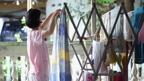 Young-Asian-woman-to-hang-dry-the-clothes-with-the-background-of-the-people's-traffic