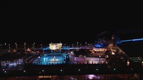 Aerial-drone-shot-over-a-hiphop-pool-party-on-the-top-of-a-cruise-ship-off-the-Lahaina-shores,-Hawaii,-USA-at-night-time