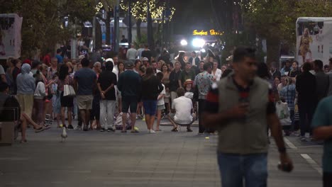 Crowds-gathered-in-a-circle-in-the-middle-of-cavill-avenue-watching-street-busking-performance-at-night-at-surfers-paradise,-Gold-Coast,-Queensland,-Australia