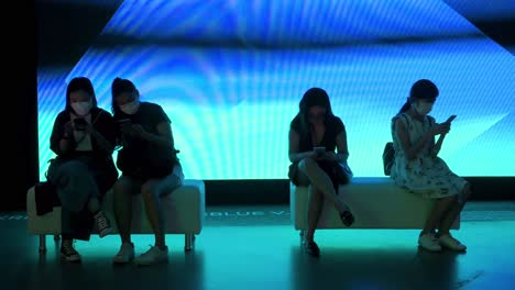 Chinese-visitors-rest-as-they-use-their-smartphones-in-front-of-the-art-installation-at-the-Digital-Art-Fair-showcasing-upcoming-trends-such-as-Web-3