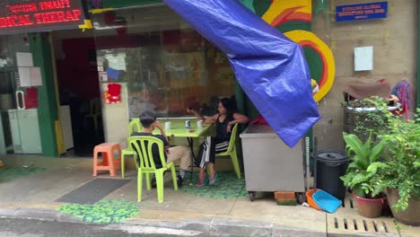 Friends-sit-outside-a-motel-chit-chatting-in-Changkat-Bukit-Bintang,-Kuala-Lumpur,-Malaysia