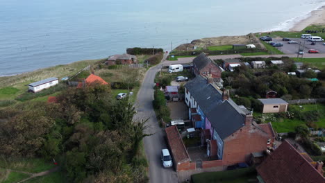An-aerial-view-of-Happisburgh-village-beach-road-that-ends-abruptly-due-increased-coastal-erosion-and-the-structural-remains-of-old-buildings-poke-up-from-out-the-North-Sea-on-the-Norfolk-coastline