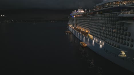 Aerial-drone-shot-over-tender-boats-unloading-and-loading-passengers-on-a-cruise-ship-in-Lahaina,-USA-on-a-dark-night
