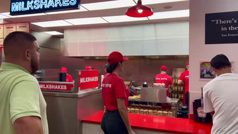 Fünf-Jungs,-Fast-Food-Burger-Restaurant,-Leute,-Die-Auf-Ihre-Bestellung-Warten,-Angestellte,-Die-In-Der-Küche-Arbeiten,-4k-Aufnahme