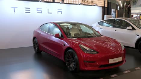Showroom-displaying-the-American-automaker-company,-Tesla-Motors,-electric-vehicles-such-as-model-X-car-in-red-at-a-retail-shopping-mall-in-Hong-Kong