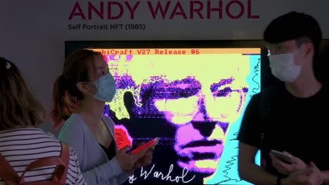 Los-Visitantes-Chinos-Se-Ven-Frente-A-Una-Obra-De-Arte-De-Token-No-Fungible-De-Realidad-Aumentada-Llamada-&#39;autorretrato&#39;-Del-Artista-Estadounidense-Andy-Warhol-En-La-Feria-De-Arte-Digital-Que-Muestra-Las-Próximas-Tendencias