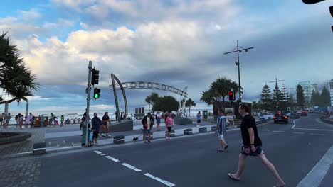 Pedestrians-crossing-the-street,-strolling-on-along-the-esplanade-towards-the-beach-at-surfers-paradise,-Gold-Coast,-Queensland,-Australia