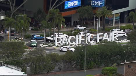 Stationary-timelapse-close-up-shot-of-front-entrance-of-pacific-fairs-shopping-centre,-car-driving-at-the-gated-roundabout-exit-to-Hooker-Blvd,-Broadbeach,-Gold-Coast,-Queensland,-Australia