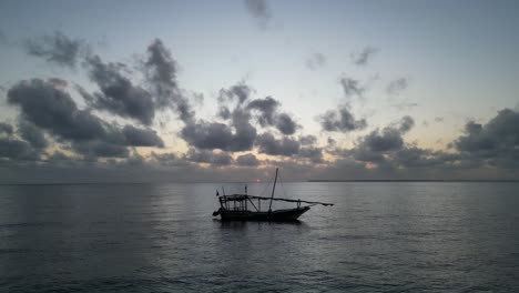 Fishing-boat-floating-near-the-shore-during-dark-sunset,-Aerial-flythrough-shot