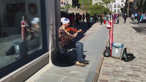 Street-Musician-playing-fiddle-and-tapping-feet-in-Quebec-City,-Canada