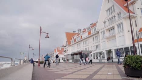 Menschen-An-Der-Promenade-Von-De-Haan-Beach-Mit-Strandgeschäften-Tagsüber-In-De-Haan,-Belgien