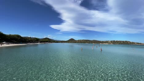 Wide-panoramic-view-of-beautiful-Santa-Giulia-famous-French-Corsican-heavenly-beach-with-crystalline-turquoise-sea-water-and-people-on-vacation-sunbathing-on-hot-summer-day