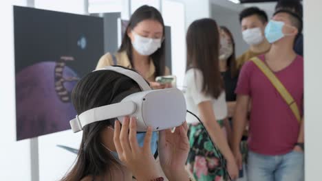 An-art-visitor-uses-a-Virtual-Reality-headset-to-interact-with-an-immersive-artwork-as-other-attendees-queue-in-line-at-the-Digital-Art-Fair-showcasing-upcoming-trends