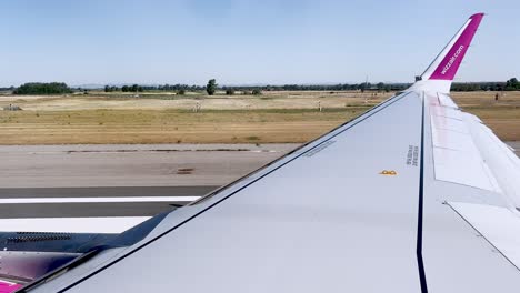 Fisrt-part-of-passenger-point-of-view-of-Wizzair-aircraft-wing-during-take-off-from-Rome-Fiumicino-Airport-runway,-Italy
