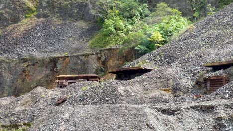 Abandoned-mining-trucks-buried-under-earth-and-gravel-inside-closed-Panguna-Mine-in-remote-tropical-island-of-Bougainville,-Papua-New-Guinea