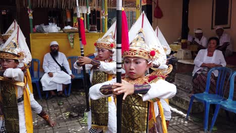 Niños-Balineses-Interpretando-Baris,-La-Danza-Guerrera,-Ceremonia-Religiosa-Hindú-Bali,-Dentro-De-Un-Templo-Familiar-Con-Trajes-Coloridos-Y-Lanzas