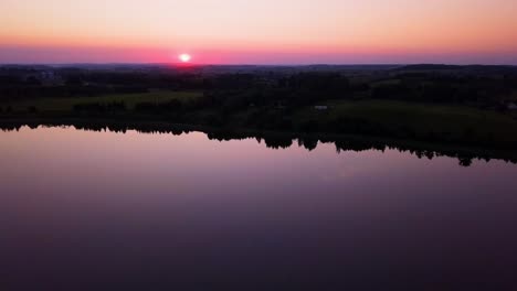 Farbenfroher-Sonnenuntergang-über-Einem-Friedlichen-See,-Umgeben-Von-Bäumen